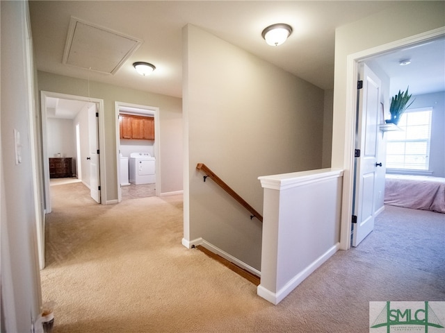 corridor with washing machine and dryer and light carpet