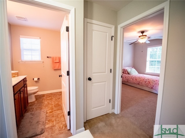 bathroom featuring a wealth of natural light, toilet, vanity, and ceiling fan