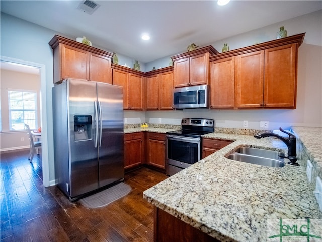 kitchen featuring appliances with stainless steel finishes, dark hardwood / wood-style floors, light stone counters, and sink