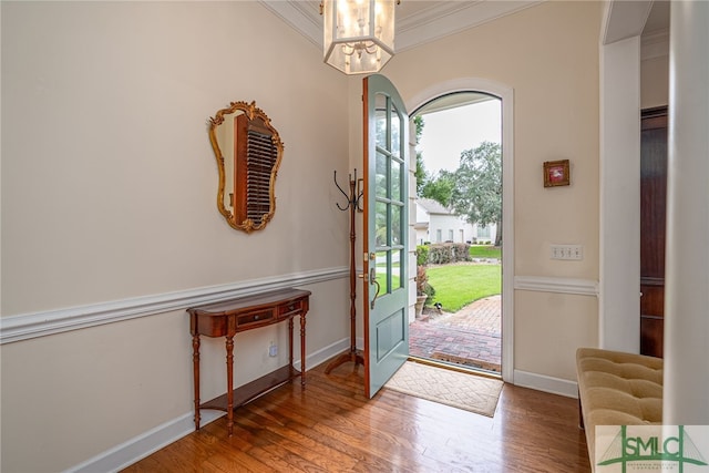 entryway featuring an inviting chandelier, hardwood / wood-style flooring, and ornamental molding