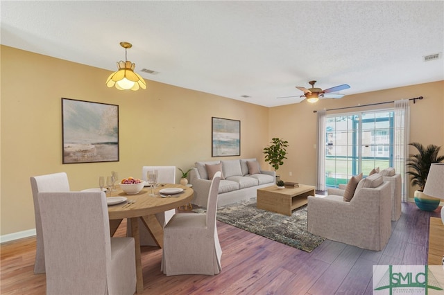 living room with ceiling fan, light hardwood / wood-style flooring, and a textured ceiling