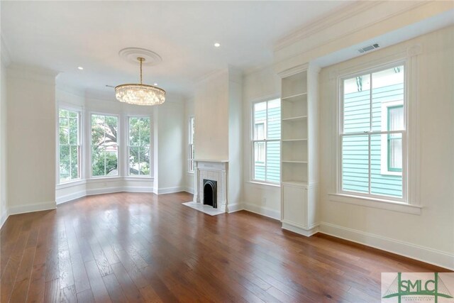 unfurnished living room with a fireplace, ornamental molding, dark hardwood / wood-style floors, and a notable chandelier