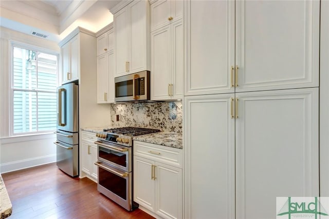 kitchen with plenty of natural light, dark hardwood / wood-style flooring, light stone counters, and stainless steel appliances