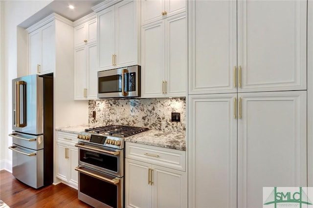 kitchen featuring light stone countertops, decorative backsplash, premium appliances, and dark wood-type flooring