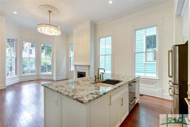 kitchen with stainless steel refrigerator, sink, hanging light fixtures, dark hardwood / wood-style floors, and white cabinets