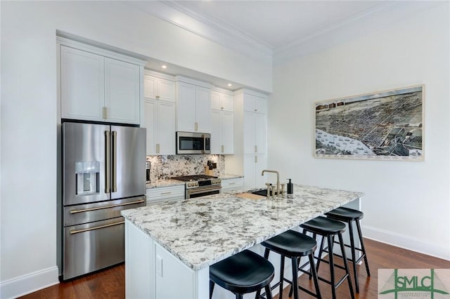 kitchen featuring a breakfast bar area, white cabinetry, an island with sink, and stainless steel appliances