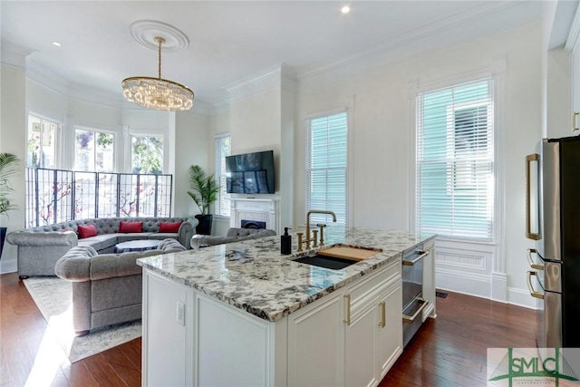 kitchen featuring sink, dark hardwood / wood-style floors, stainless steel fridge, decorative light fixtures, and white cabinets