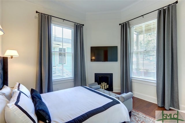 bedroom with hardwood / wood-style flooring, multiple windows, and ornamental molding