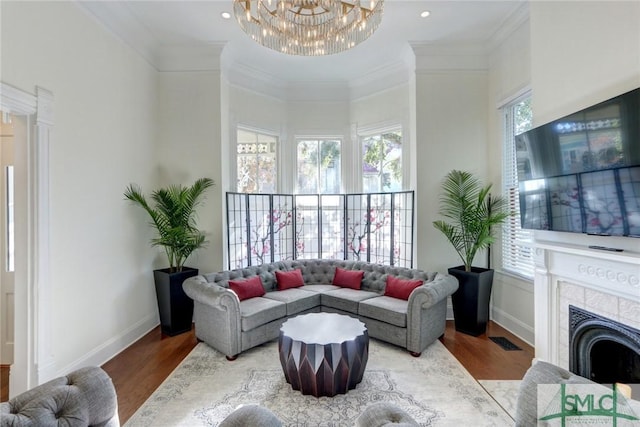 living room with crown molding, hardwood / wood-style flooring, a towering ceiling, a fireplace, and a chandelier