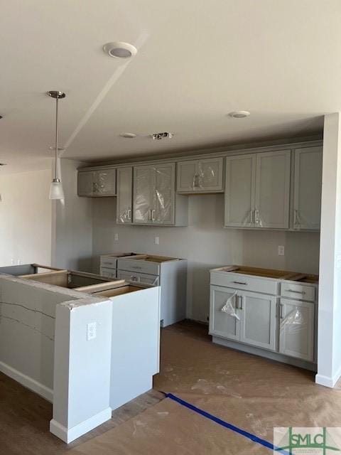 kitchen featuring gray cabinets, concrete flooring, and pendant lighting