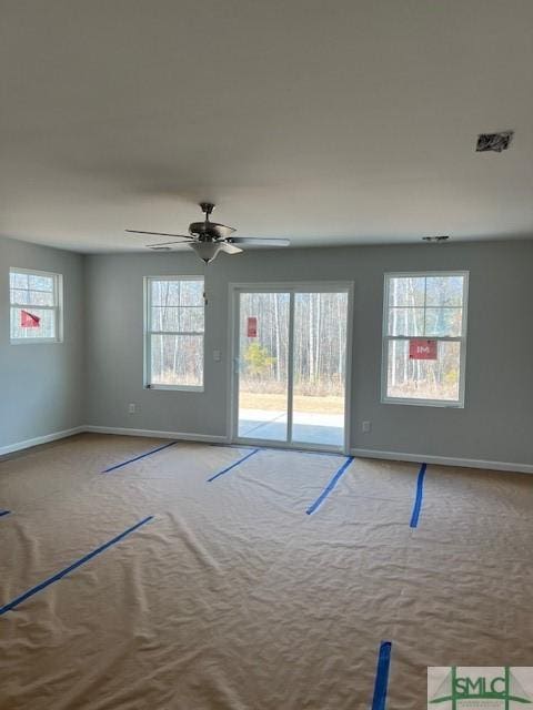 carpeted empty room featuring a wealth of natural light and ceiling fan