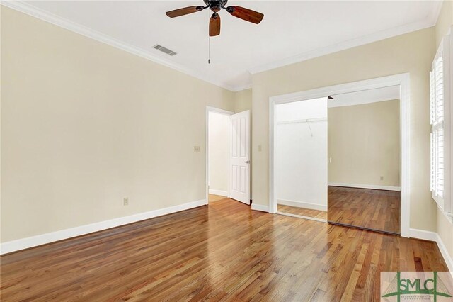 unfurnished bedroom with a closet, crown molding, ceiling fan, and hardwood / wood-style flooring