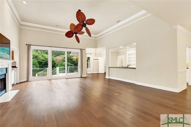 unfurnished living room featuring dark hardwood / wood-style floors, ceiling fan, crown molding, and sink