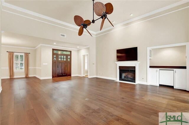 unfurnished living room featuring hardwood / wood-style flooring, ceiling fan, and crown molding