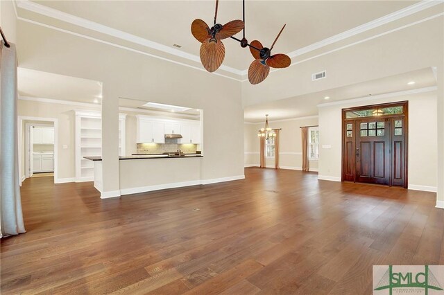 unfurnished living room with dark hardwood / wood-style flooring, a notable chandelier, and ornamental molding