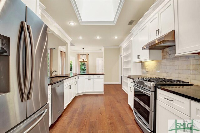 kitchen with white cabinetry, sink, wood-type flooring, decorative light fixtures, and appliances with stainless steel finishes