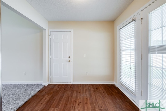 spare room featuring dark hardwood / wood-style floors and a textured ceiling