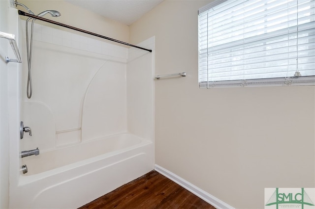 bathroom with wood-type flooring, shower / bathing tub combination, and a textured ceiling