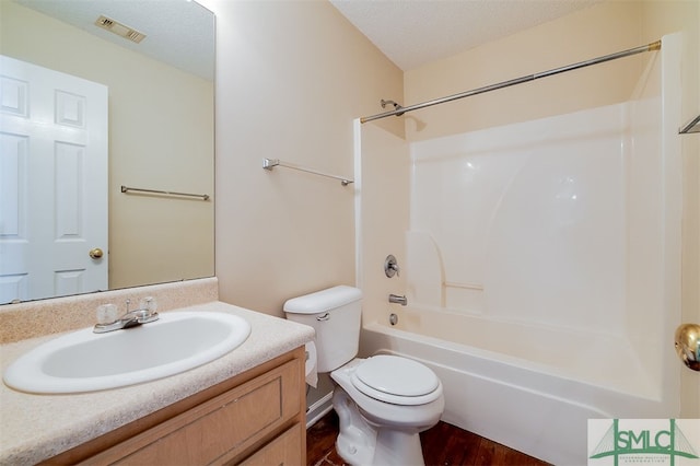 full bathroom with vanity, a textured ceiling, hardwood / wood-style flooring, bathing tub / shower combination, and toilet