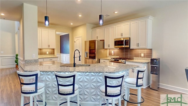 kitchen featuring hanging light fixtures, sink, white cabinets, and stainless steel appliances