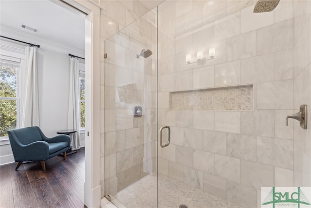 bathroom with ornamental molding, hardwood / wood-style flooring, and a shower with shower door