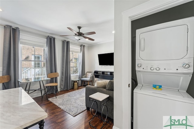 laundry area featuring ceiling fan, crown molding, stacked washer / dryer, and dark hardwood / wood-style flooring