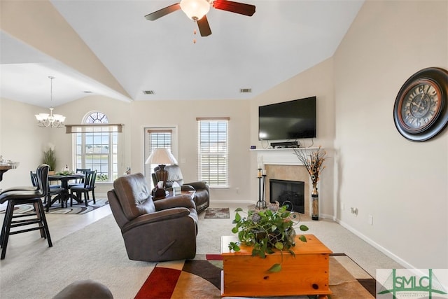 carpeted living room with ceiling fan with notable chandelier, lofted ceiling, and a tiled fireplace