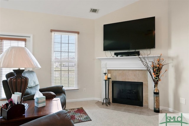 living room with light colored carpet, a tile fireplace, lofted ceiling, and a wealth of natural light