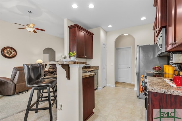 kitchen with kitchen peninsula, a kitchen bar, and ceiling fan