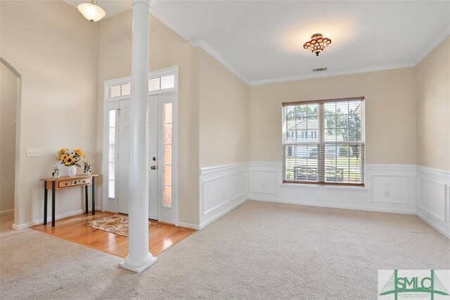 carpeted foyer featuring ornamental molding and decorative columns