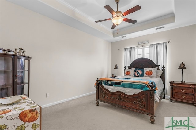 bedroom with ceiling fan, a tray ceiling, light carpet, and crown molding