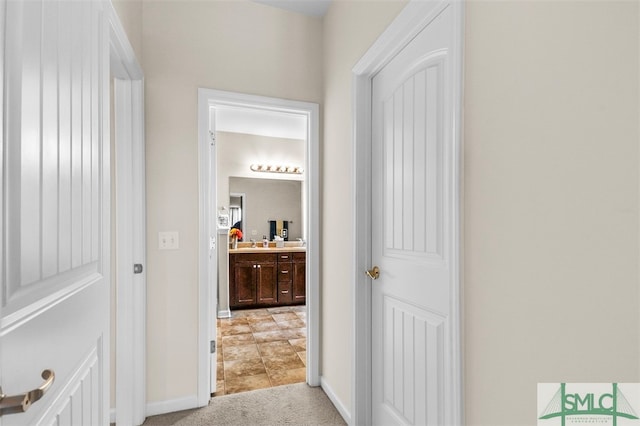 hall featuring sink and light colored carpet