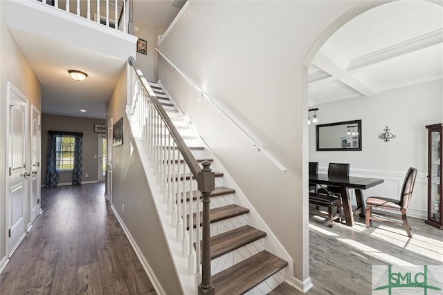 stairway with coffered ceiling, beam ceiling, and hardwood / wood-style floors