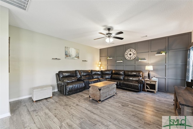 living room with ceiling fan, a textured ceiling, and light hardwood / wood-style floors