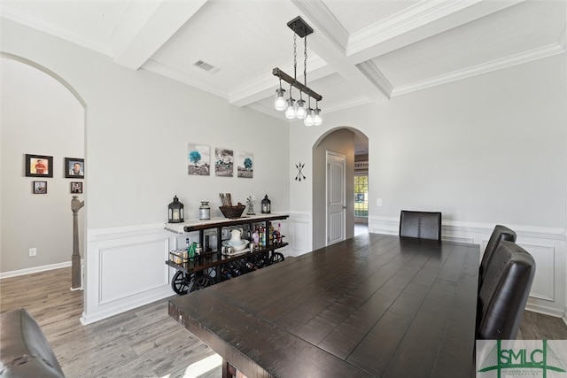 dining area featuring crown molding, beam ceiling, a chandelier, and light hardwood / wood-style floors