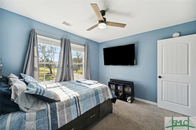 carpeted bedroom featuring ceiling fan and a textured ceiling