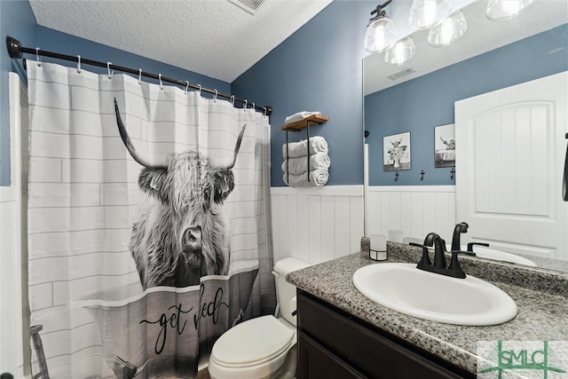 bathroom with a textured ceiling, a shower with curtain, vanity, and toilet