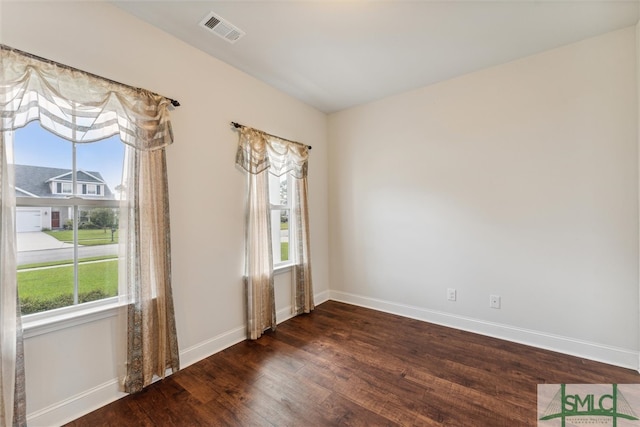 empty room featuring plenty of natural light and dark hardwood / wood-style floors