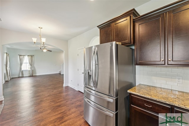 kitchen with light stone counters, ceiling fan, stainless steel fridge, dark hardwood / wood-style floors, and decorative backsplash