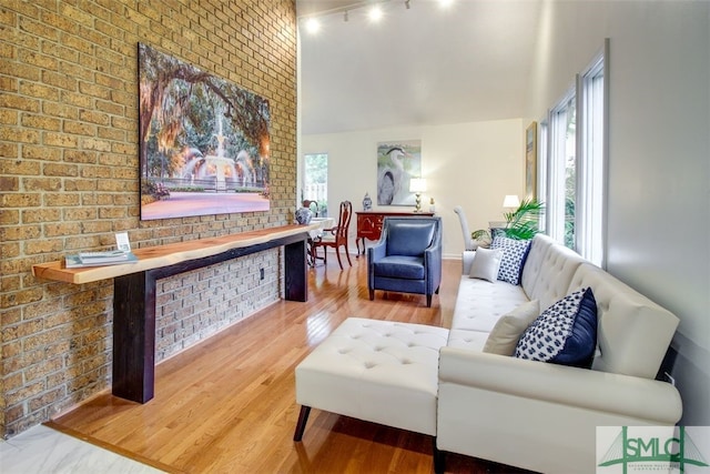 sitting room with hardwood / wood-style flooring and brick wall