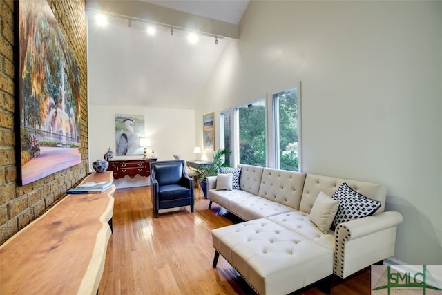 living room with hardwood / wood-style flooring, beam ceiling, track lighting, and high vaulted ceiling