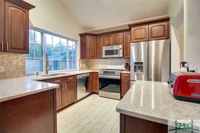 kitchen with light stone counters, lofted ceiling, sink, backsplash, and stainless steel appliances