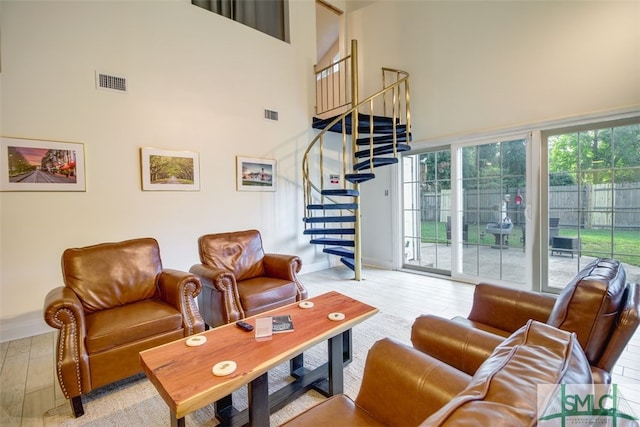 living room with a towering ceiling, light wood-type flooring, and a healthy amount of sunlight