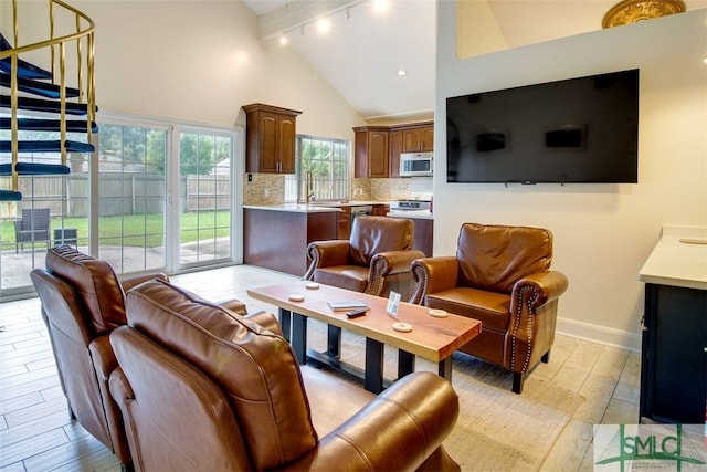 living room with beamed ceiling, high vaulted ceiling, sink, and light wood-type flooring