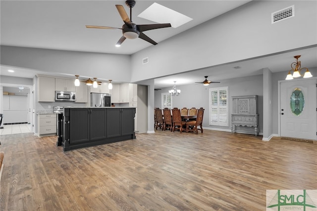 kitchen featuring wood-type flooring, white cabinets, an inviting chandelier, and stainless steel appliances