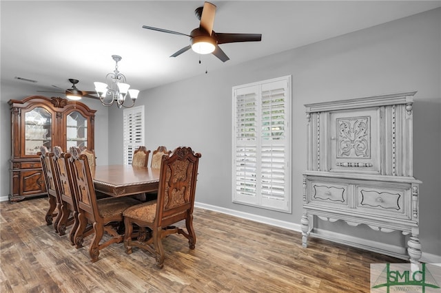 dining area with ceiling fan with notable chandelier and hardwood / wood-style flooring