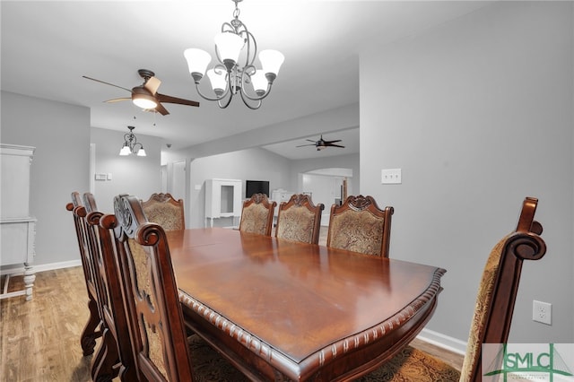 dining room with wood-type flooring and ceiling fan with notable chandelier