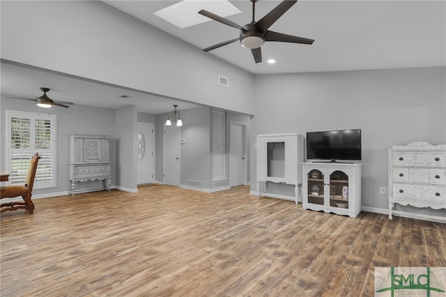 unfurnished living room featuring hardwood / wood-style flooring, ceiling fan, and lofted ceiling with skylight