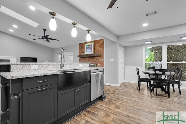 kitchen with light wood-type flooring, ceiling fan, sink, dishwasher, and light stone countertops