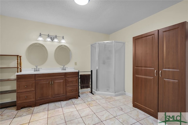 bathroom with a shower with shower door, vanity, and a textured ceiling